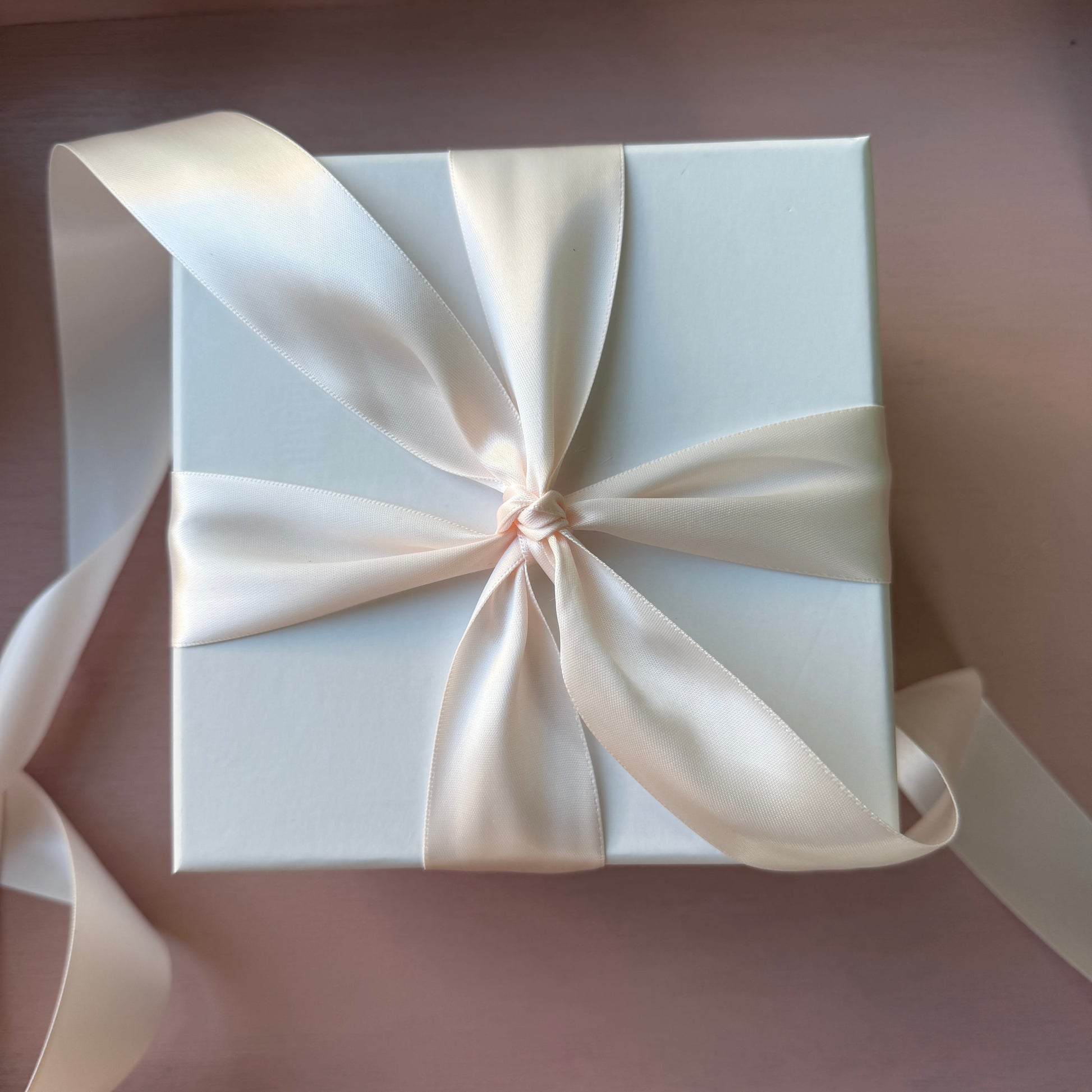 White gift box with a large bow on a matching background