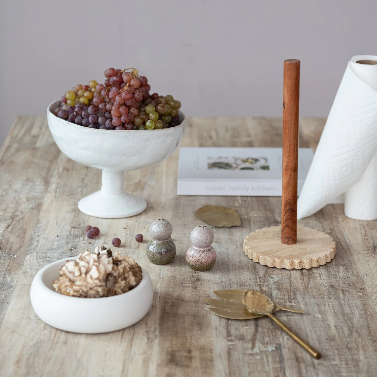 A white stoneware footed bowl with a reactive crackle glaze is displayed on a wooden table. 