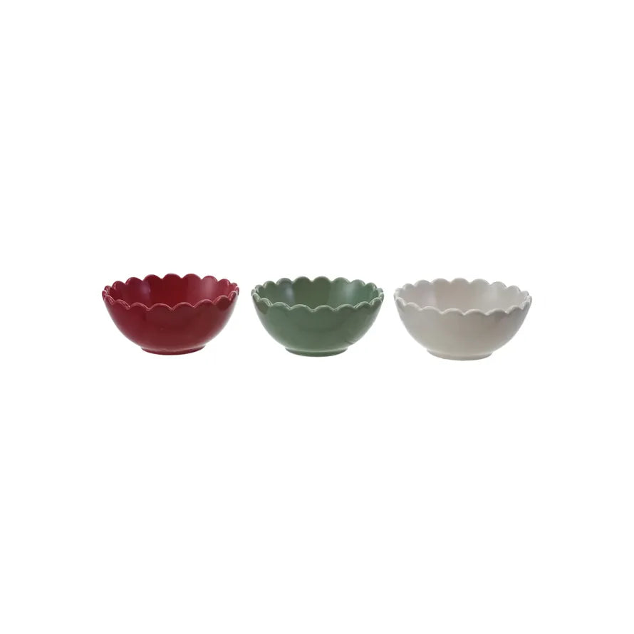 Three small stoneware bowls in red, green, and white on a white background
