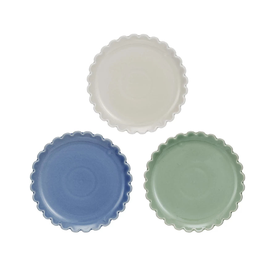 A set of three stoneware plates with scalloped edges, in blue, cream, and green colors.