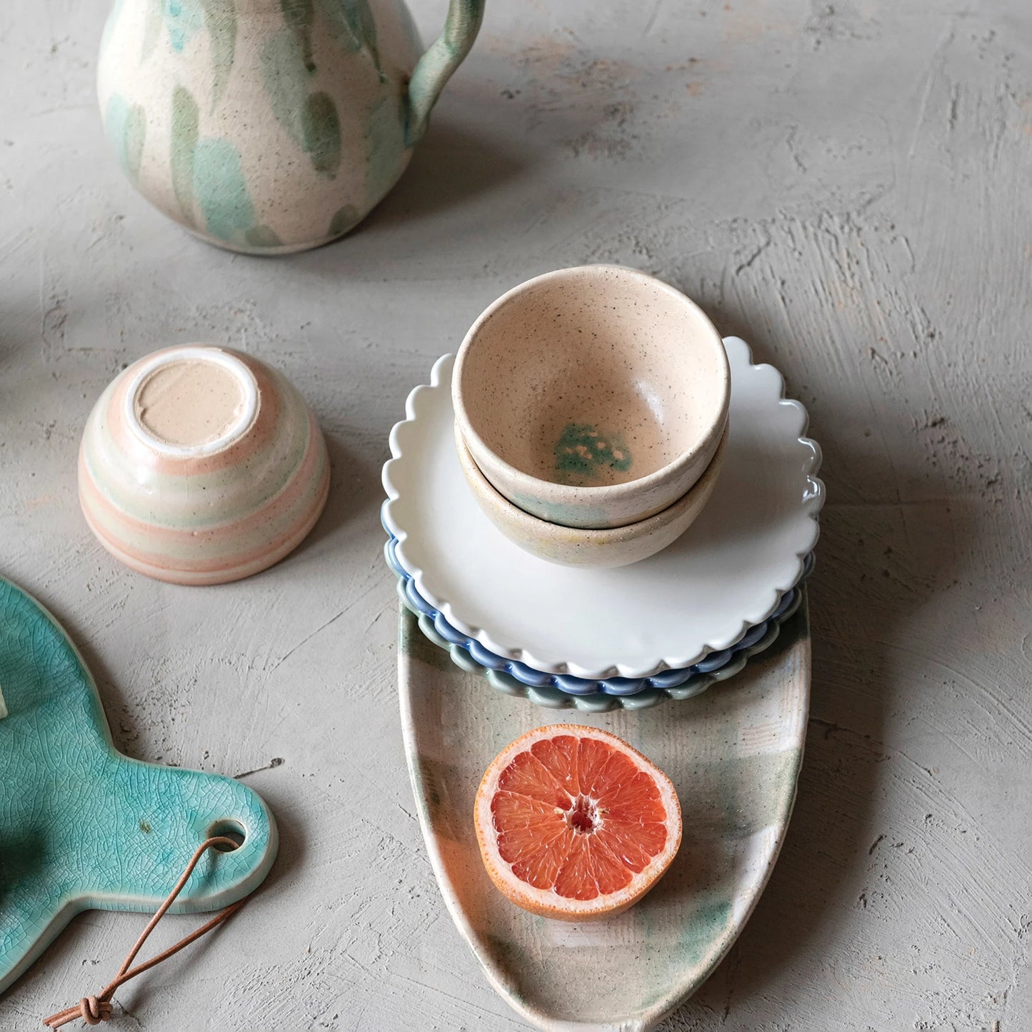 A set of three stoneware plates with scalloped edges, in blue, cream, and green colors.