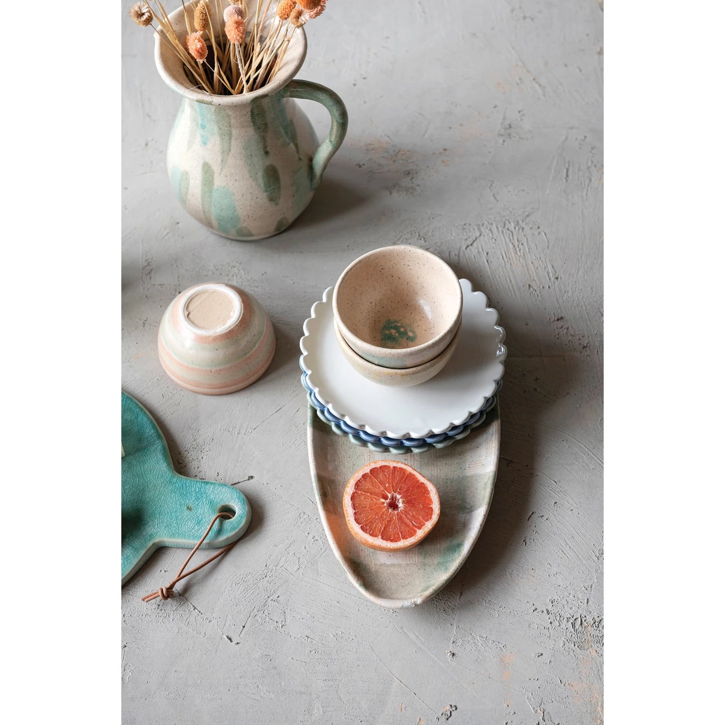 A set of three stoneware plates with scalloped edges, in blue, cream, and green colors.