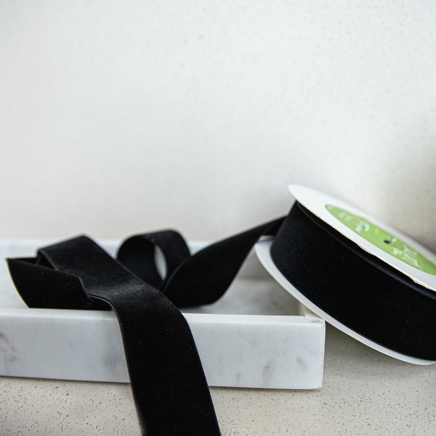 Black ribbon on a marble tray with a white background