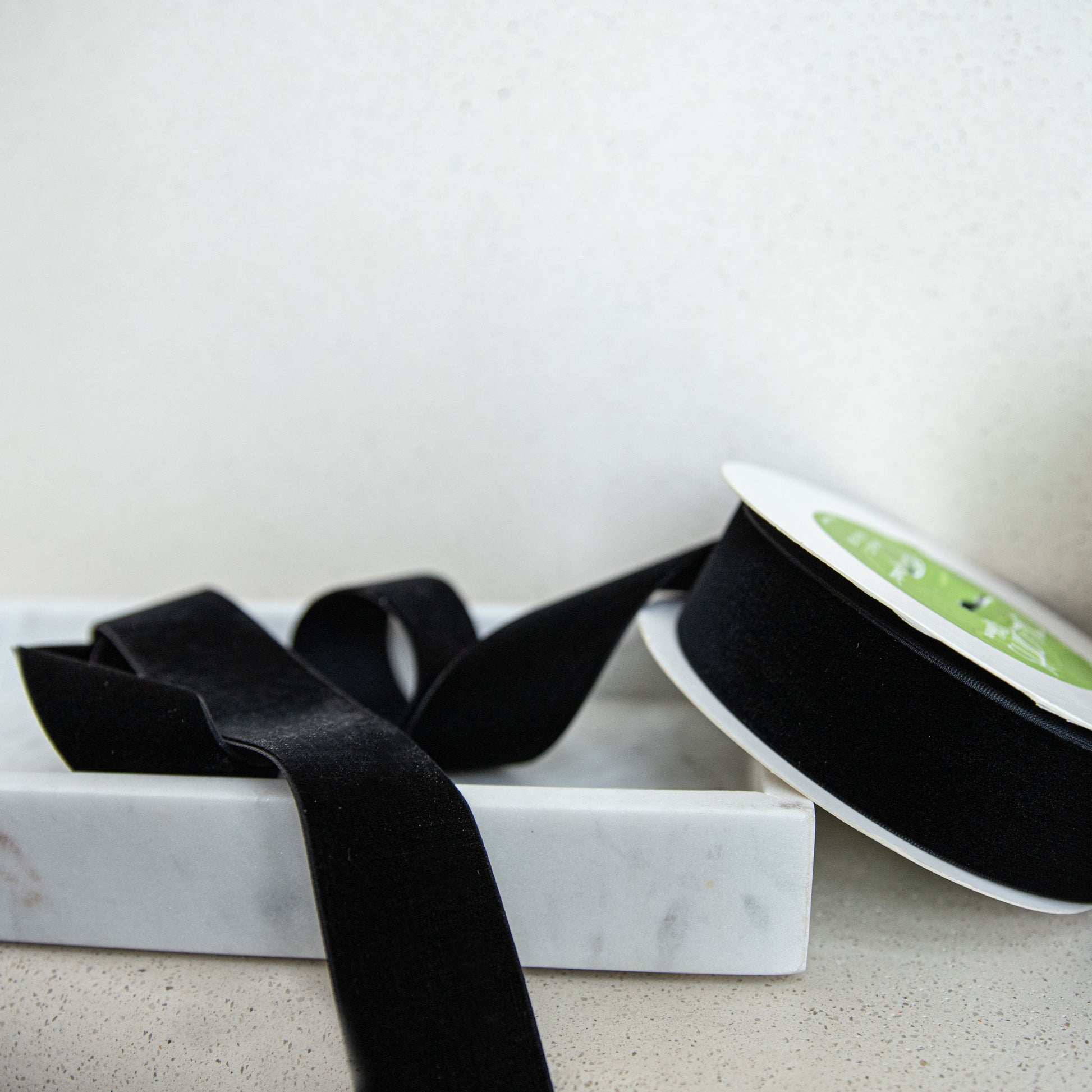 Black ribbon on a marble tray with a white background