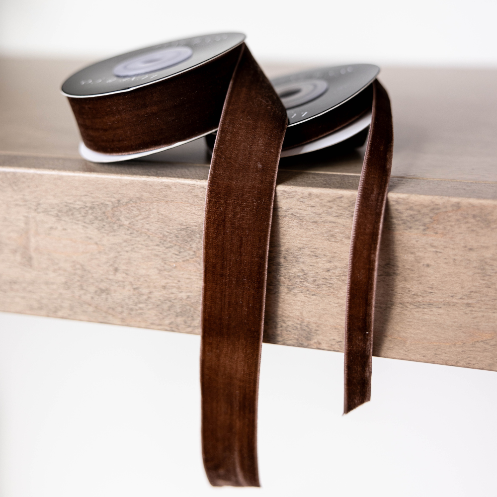 Brown ribbon spool on a wooden surface with a white background