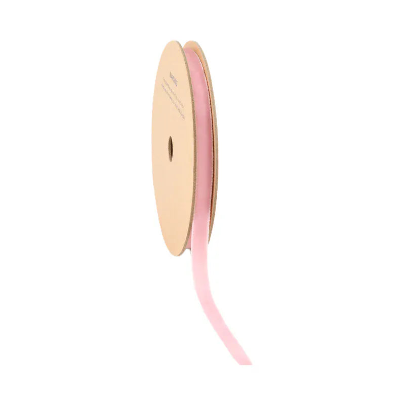Spool of pink ribbon on a beige reel against a white background