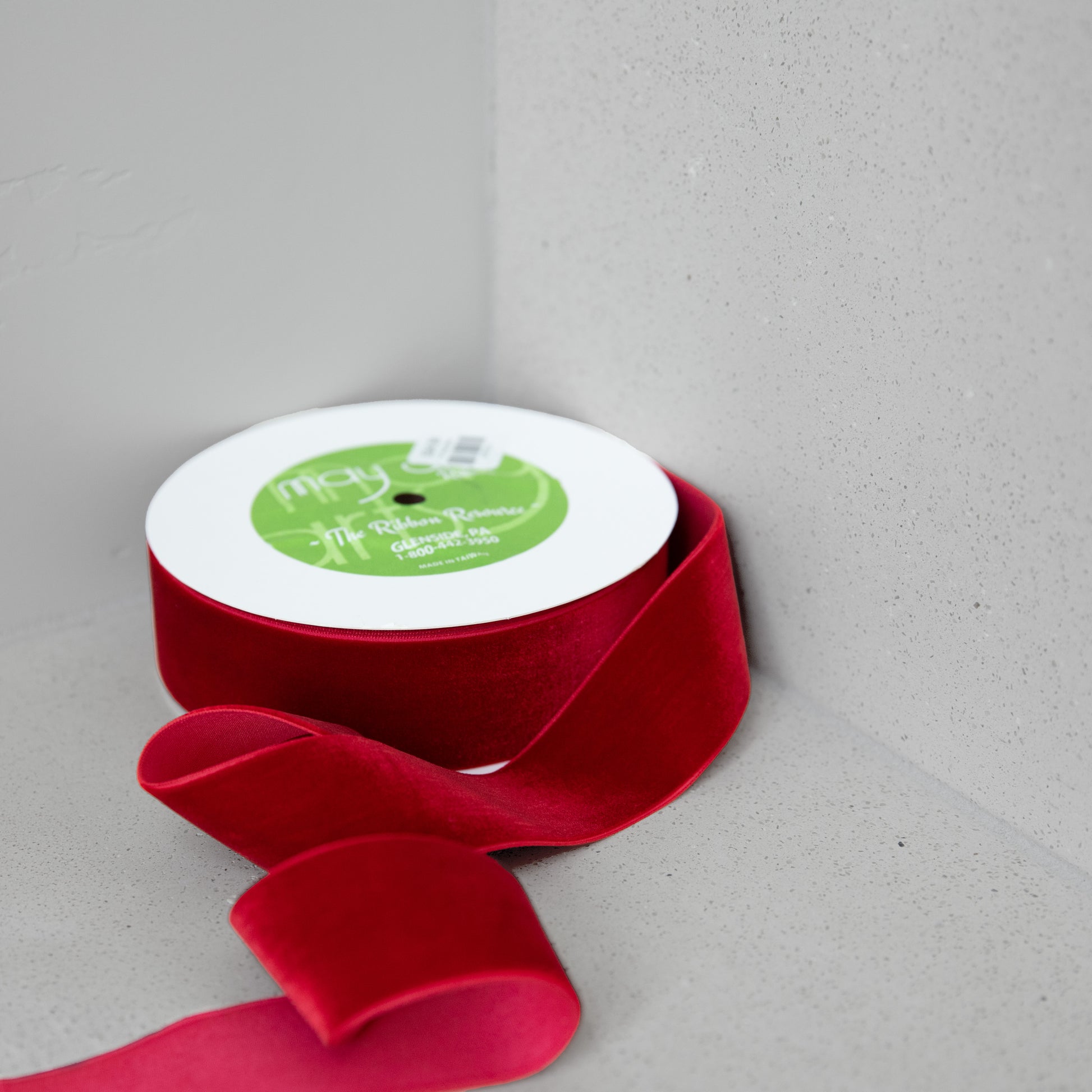 Red ribbon with a white spool on a gray background