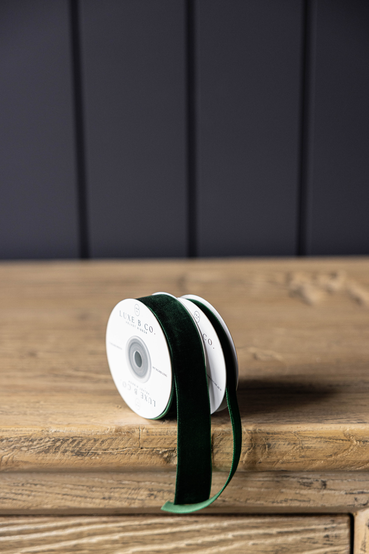 Spool of green ribbon on a wooden surface with a dark background