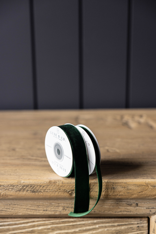 Spool of green ribbon on a wooden surface with a dark background