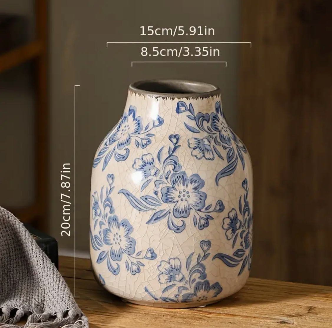 A vintage blue and white ceramic vase with floral patterns, placed on a wooden surface.