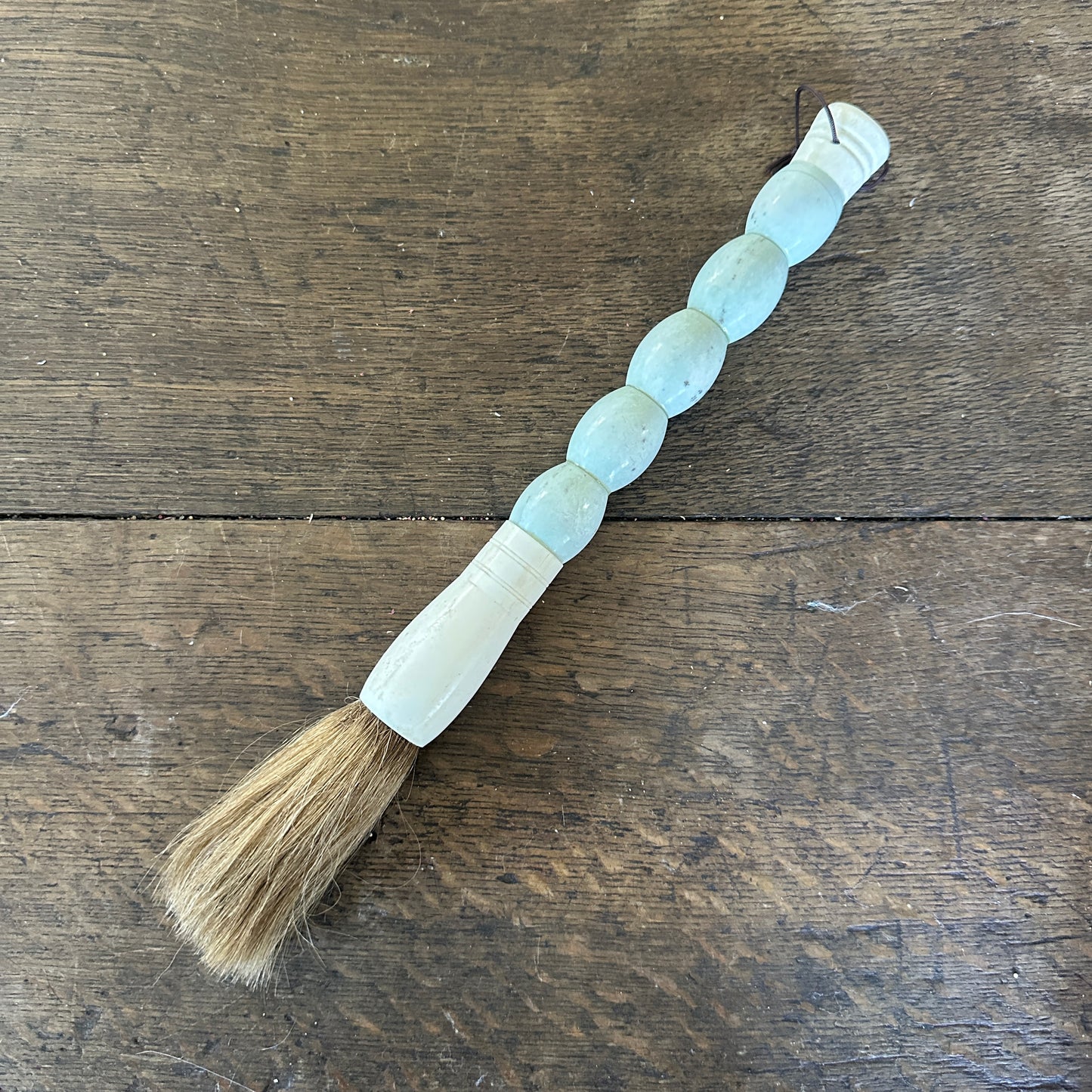 Bristled brush with a wooden handle on a wooden surface White Cylindrical Jade Calligraphy Brush 