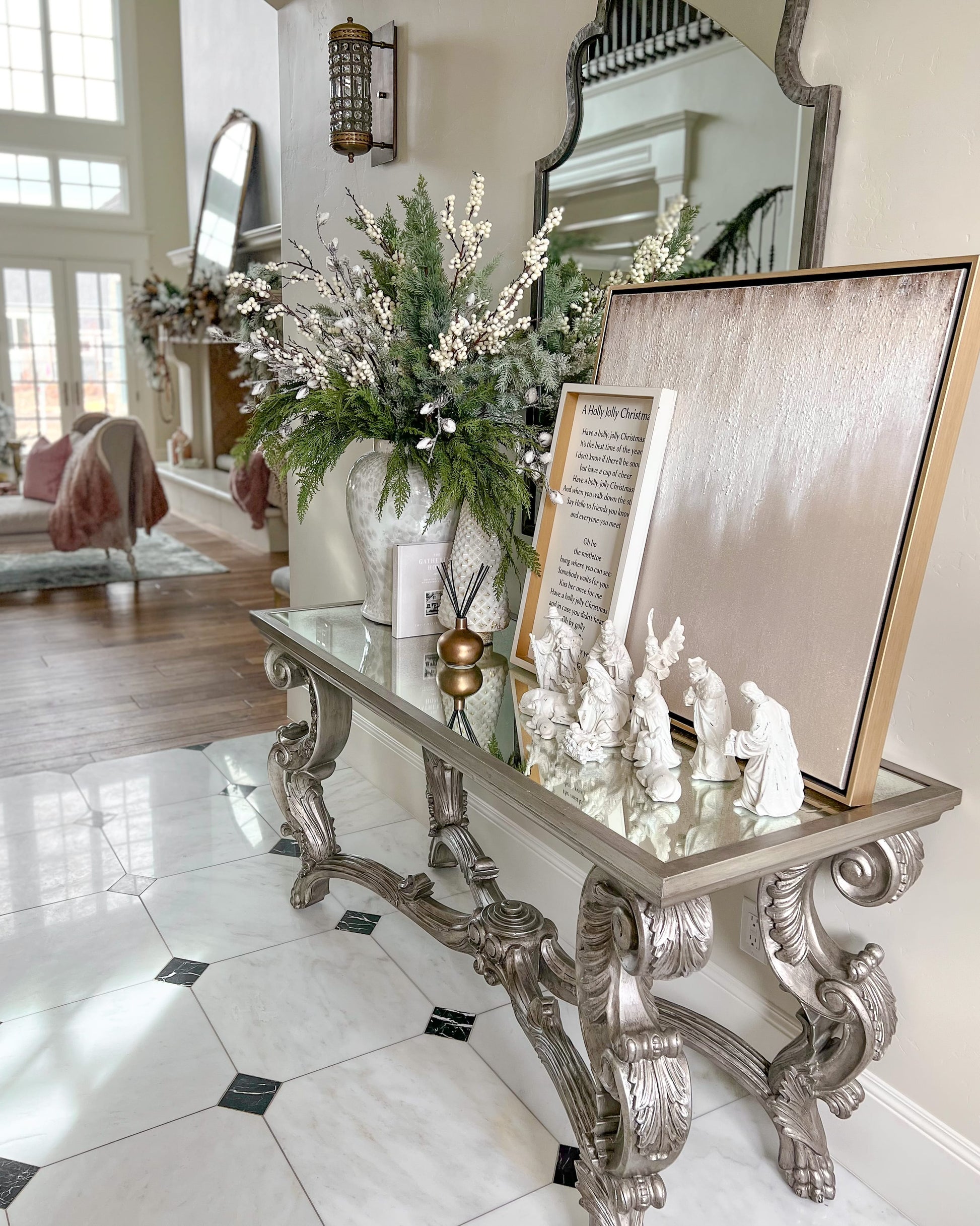 Decorative console table with Christmas nativity scene and floral arrangement in a living room.