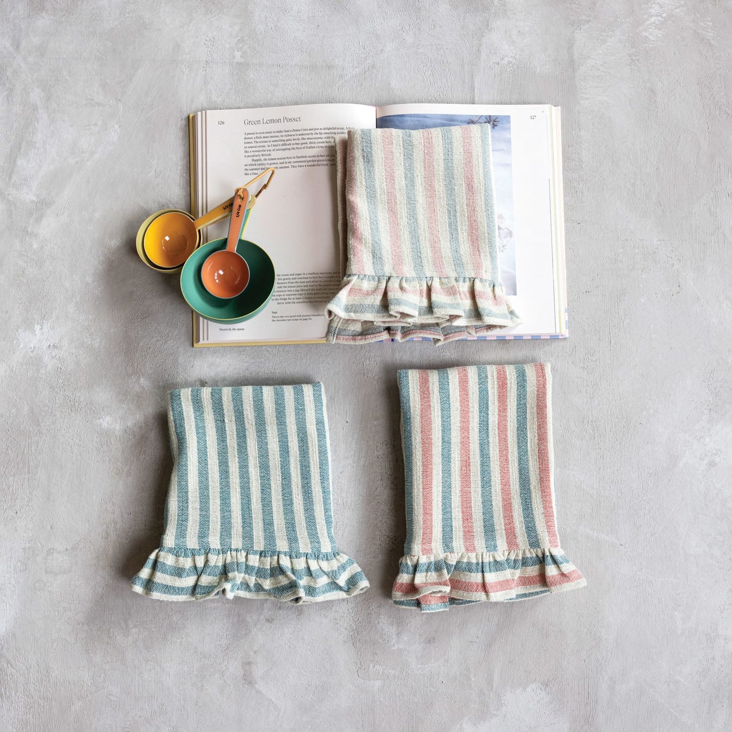 Three woven cotton tea towels with stripes and ruffles, displayed side by side. From left to right: blue stripes, red and blue stripes, light pink and light green stripes.
