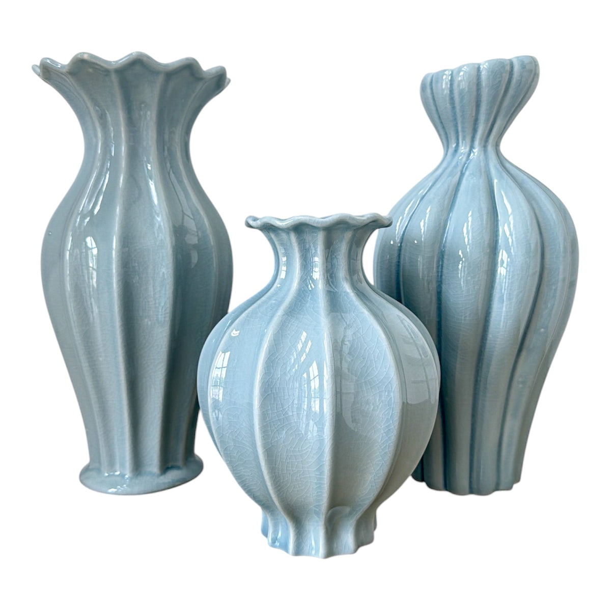 Set of three light blue ceramic vases with textured design on a white background