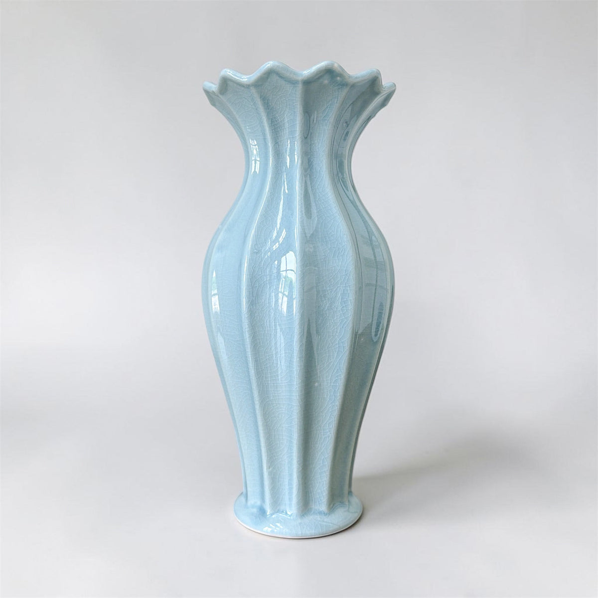 Light blue ceramic vase with a textured surface on a white background