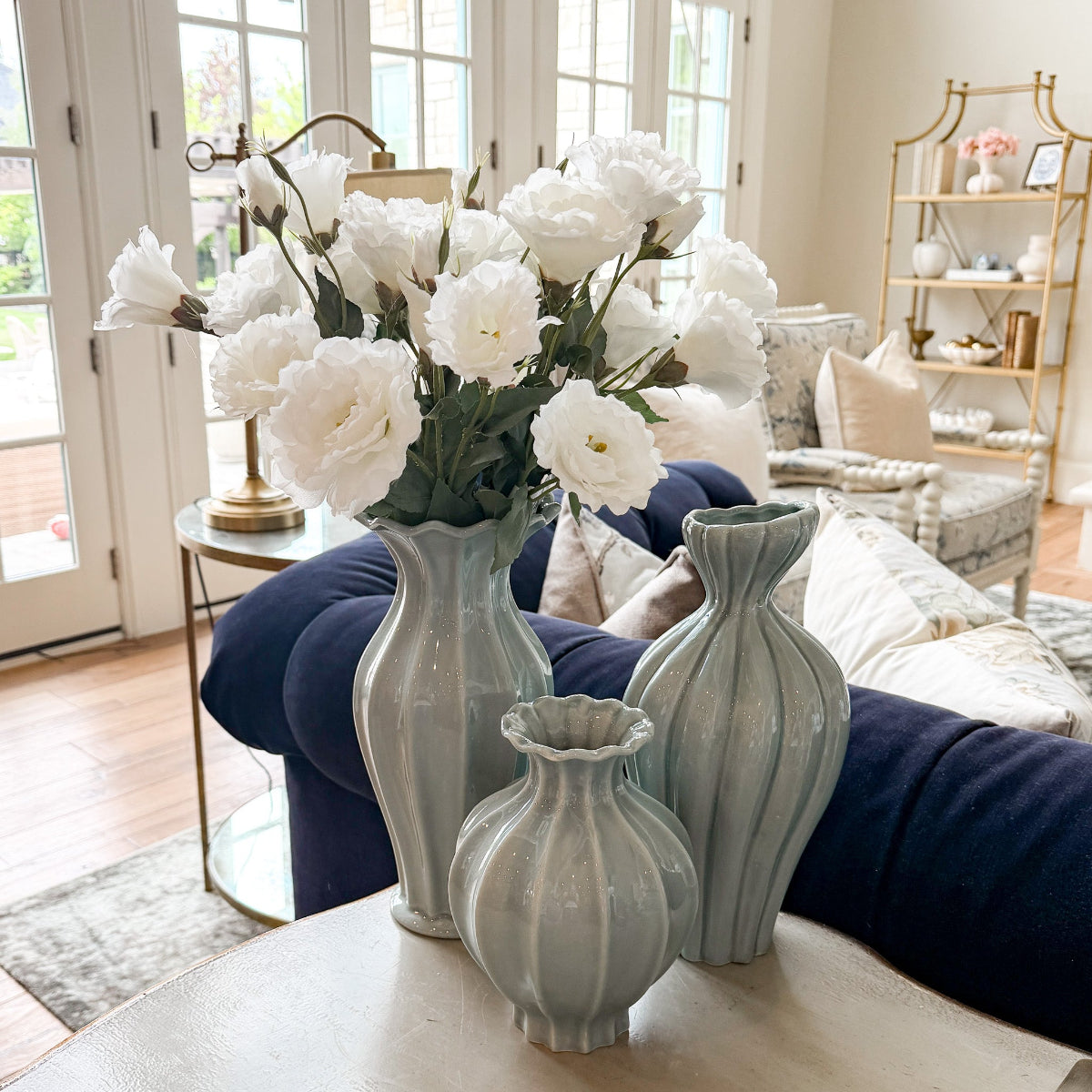 Decorative vases with white flowers on a coffee table in a living room.