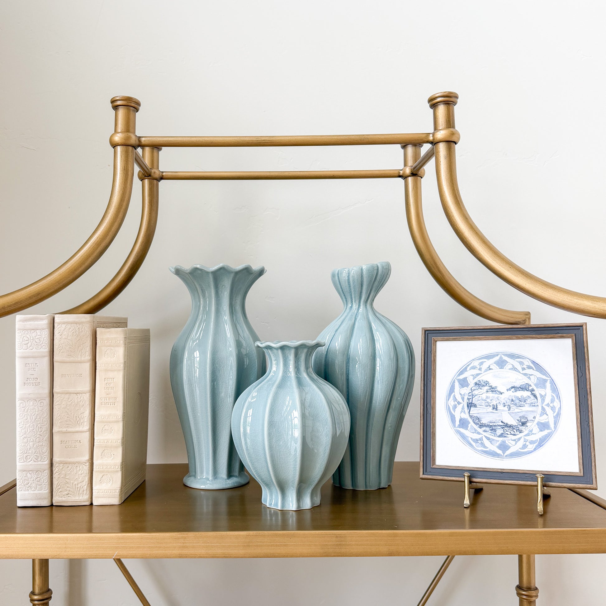 Three light blue fluted vases on a shelf
