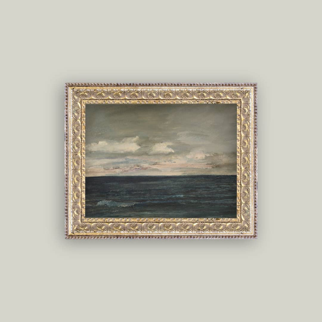 Framed painting of a landscape with ocean and sky on a light gray wall