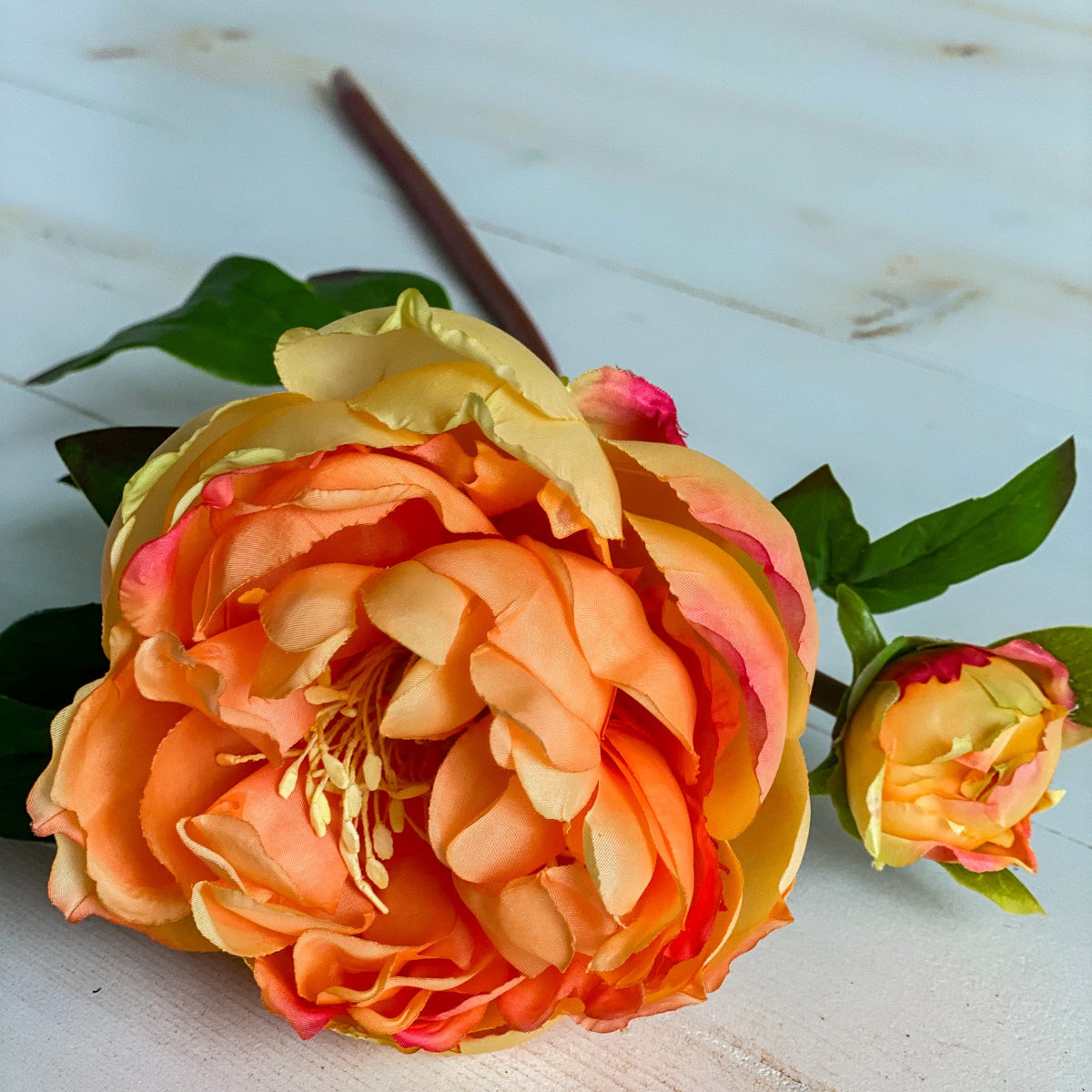 Orange and yellow artificial flower on a light wooden surface